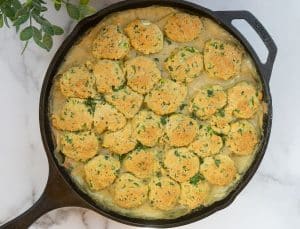 cast iron skillet full of chicken and cornbread dumplings sitting on a white countertop