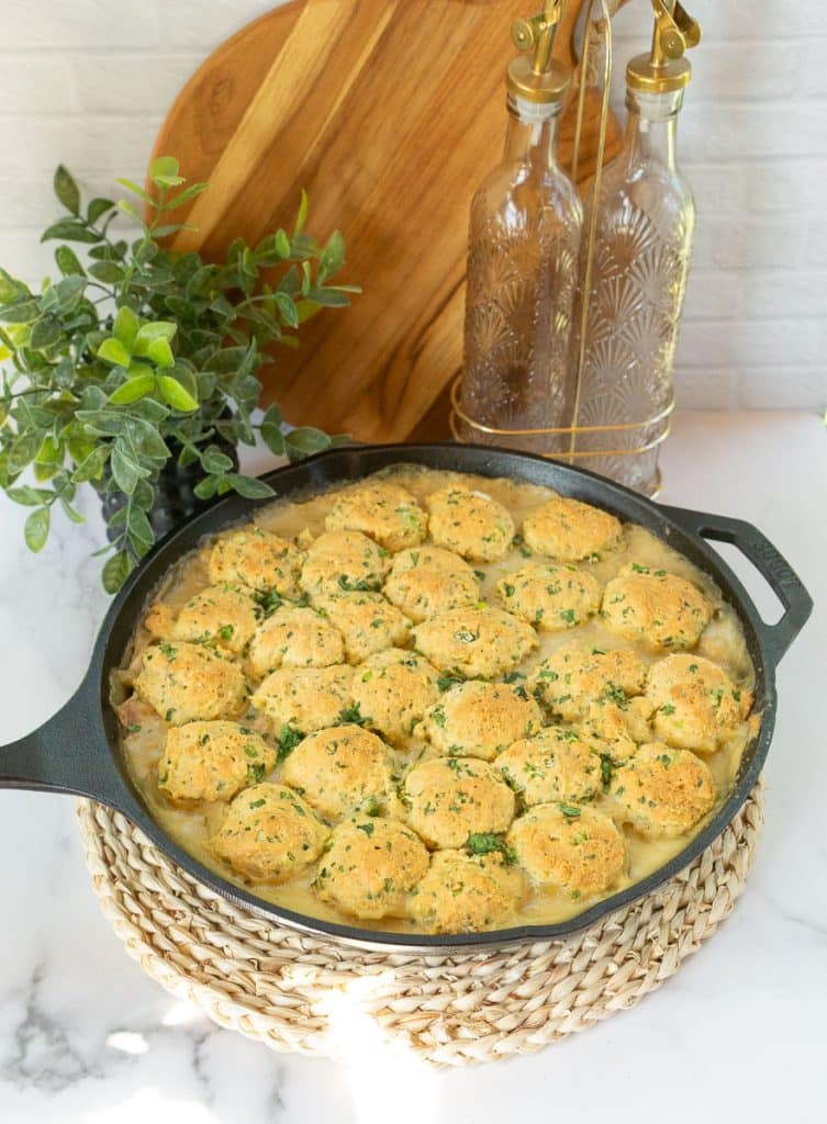 cast iron skillet of baked chicken and cornbread dumplings on a white kitchen countertop