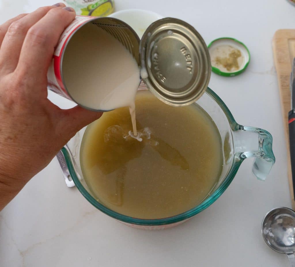 pouring evaporated milk into salsa verde and chicken stock 