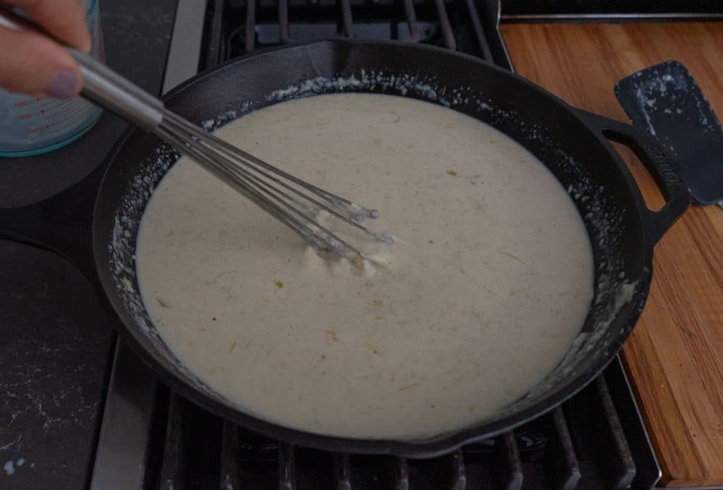 whisking gravy in cast iron skillet on stovetop