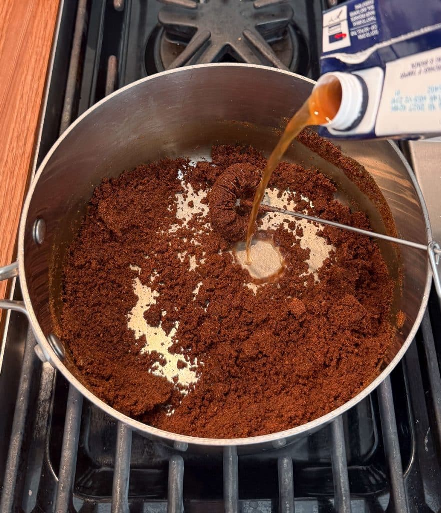 adding beef stock to the red enchilada sauce roux in medium sized sauce pan on stove top