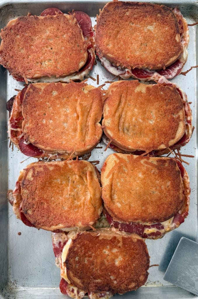 7 parmesan crusted sandwiches on a baking sheet