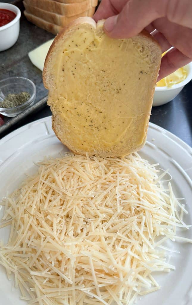 dipping buttered bread in the shredded parmesan