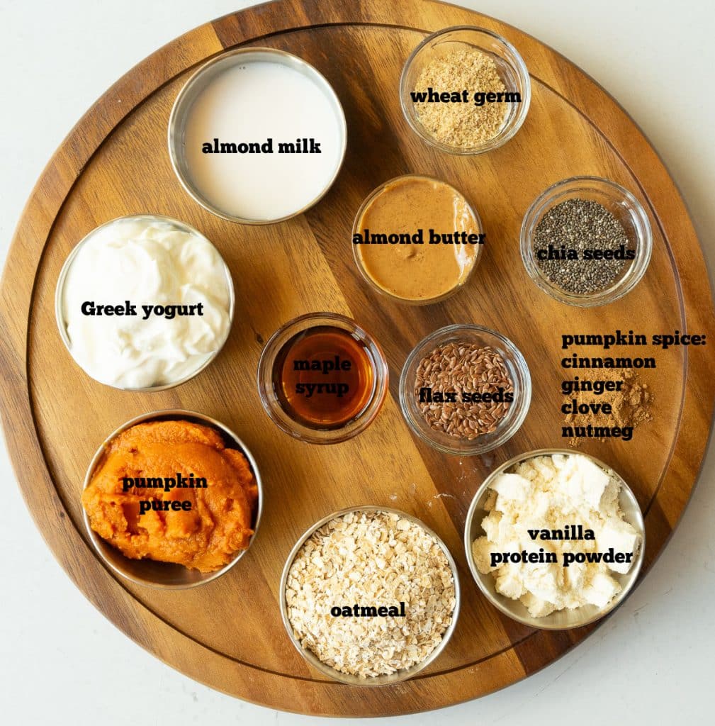 ingredients for pumpkin spice smoothie on a round cutting board on a white countertop