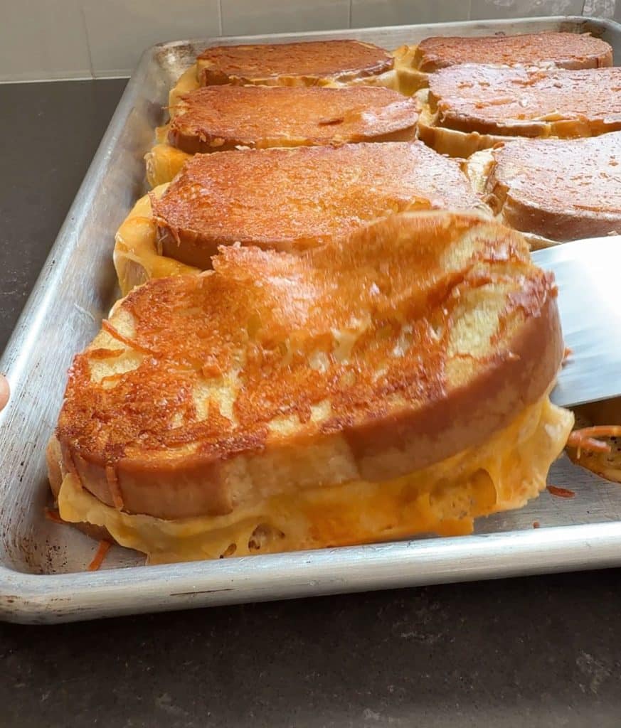 metal spatula lifting a grilled cheese of the sheet pan