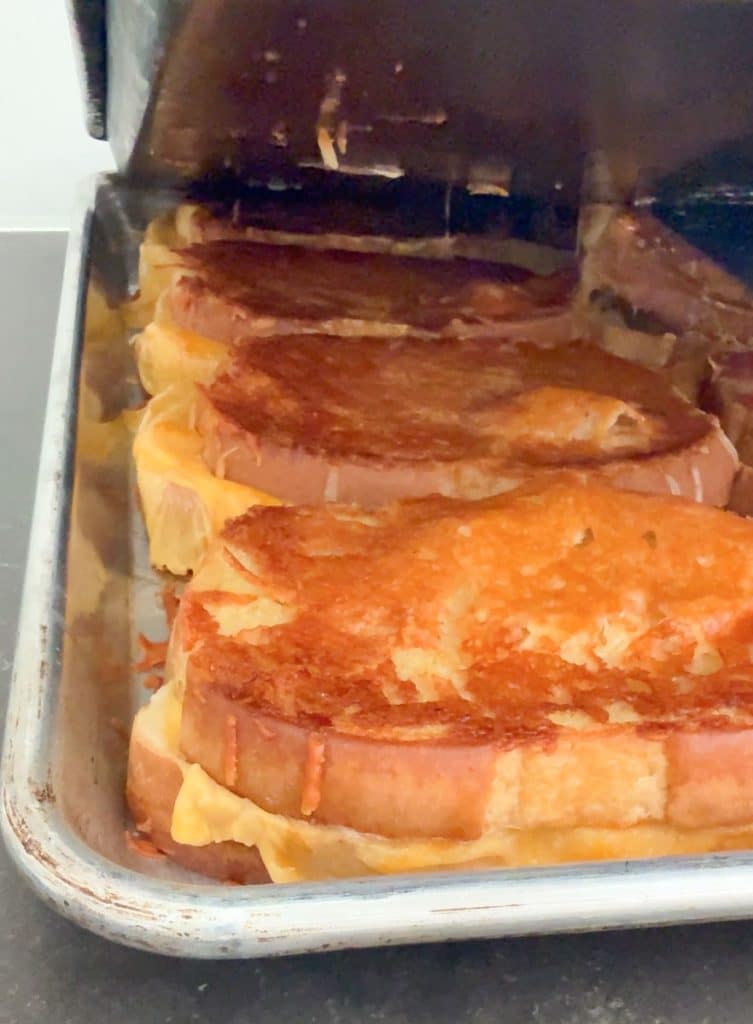 lifting top pan off the grilled cheese sandwiches revealing the perfect parmesan crusted grilled cheese sandwich