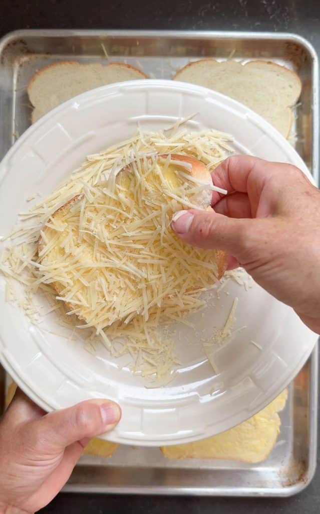 Pressing parmesan cheese on to the buttered side of white slice of bread