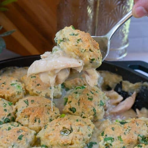 scooping chicken and dumplings out of the skillet